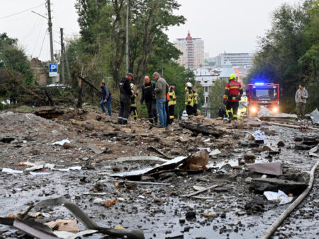 Rescue personnel and experts work on a damaged area after a Russian strike hit