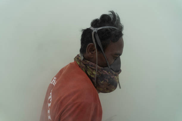 A man putting on a toxic gas mask while working.