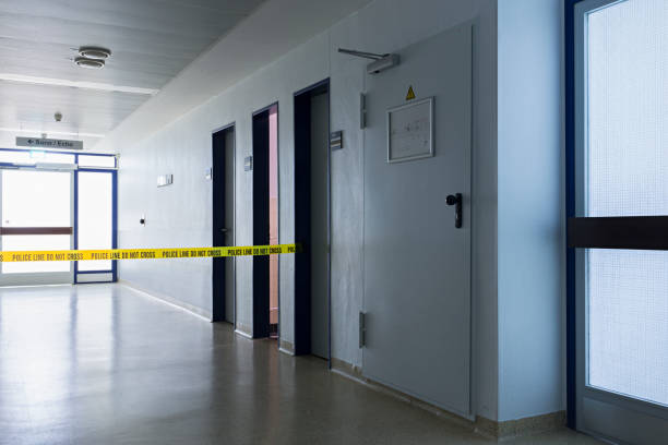 Hallway in what appears to be a secure or restricted facility. Across the hallway is yellow "Police Line Do Not Cross" tape, indicating that the area is restricted or under investigation.